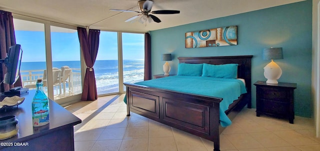 bedroom with a ceiling fan, a wall of windows, access to outside, light tile patterned floors, and a water view