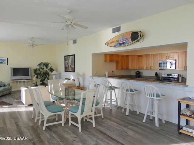 dining room featuring visible vents, a ceiling fan, and dark wood-style flooring