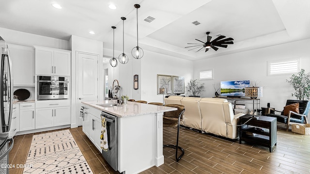 kitchen with sink, dark wood-type flooring, hanging light fixtures, white cabinets, and appliances with stainless steel finishes