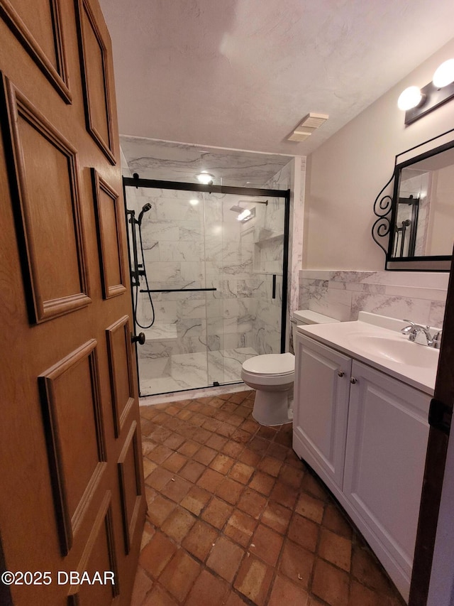 bathroom featuring tile walls, vanity, toilet, and walk in shower