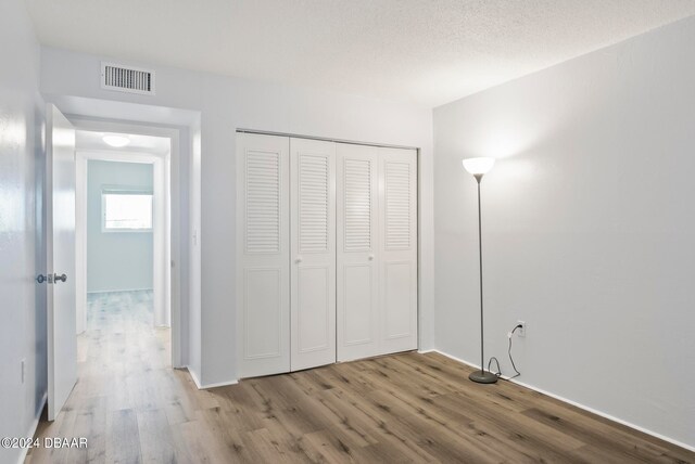 unfurnished bedroom featuring hardwood / wood-style floors, a textured ceiling, and a closet