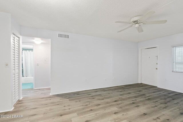 unfurnished room with a textured ceiling, light hardwood / wood-style flooring, and ceiling fan