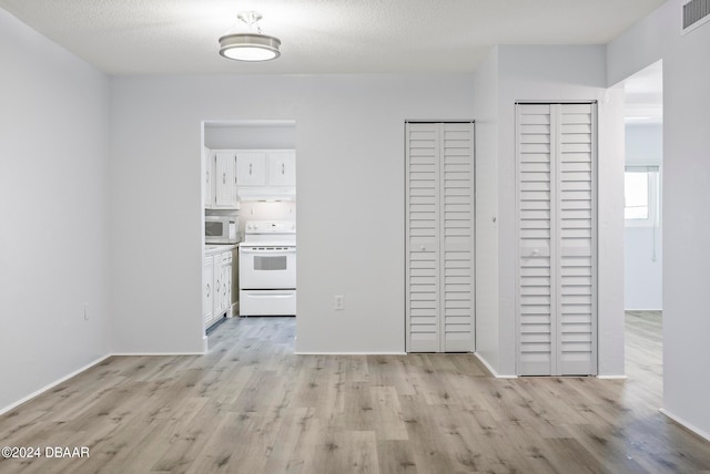 hallway with a textured ceiling and light wood-type flooring