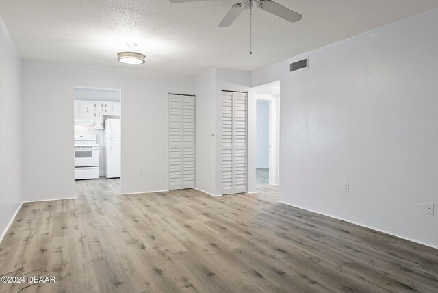 unfurnished room featuring ceiling fan, light hardwood / wood-style flooring, and a textured ceiling