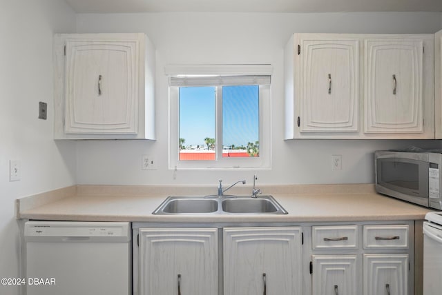 kitchen with dishwasher, white cabinetry, and sink