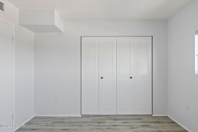 unfurnished bedroom with light hardwood / wood-style floors and a closet