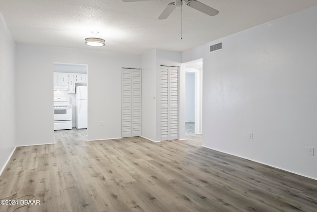 empty room with ceiling fan, a textured ceiling, and light wood-type flooring