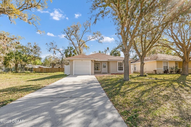 ranch-style house featuring a front yard, fence, driveway, an attached garage, and stucco siding