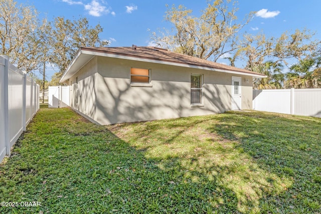 back of house with a fenced backyard, stucco siding, and a yard