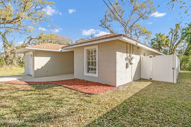 exterior space featuring stucco siding, a yard, and fence