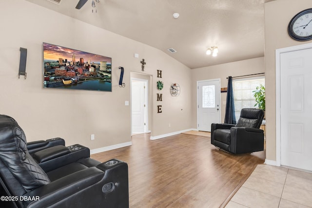 living area featuring visible vents, baseboards, lofted ceiling, and wood finished floors