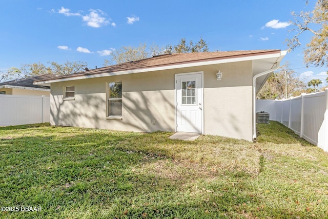 back of property with a fenced backyard, stucco siding, and a yard