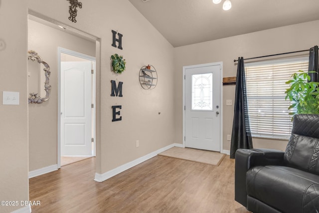 foyer entrance with light wood finished floors, baseboards, and vaulted ceiling