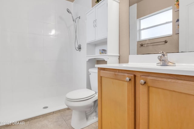 bathroom featuring tiled shower, toilet, vanity, and tile patterned flooring