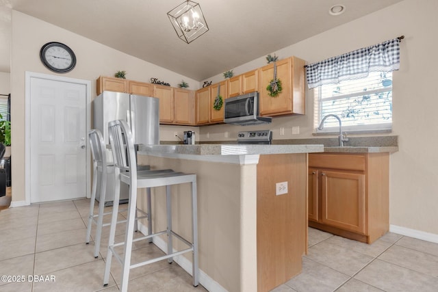 kitchen with light brown cabinets, a sink, appliances with stainless steel finishes, light tile patterned floors, and vaulted ceiling