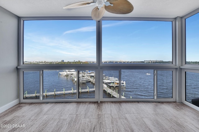 unfurnished sunroom featuring a water view and ceiling fan