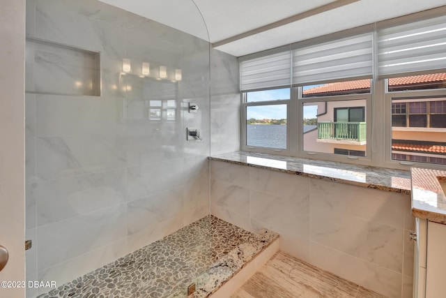 bathroom featuring a water view and a tile shower