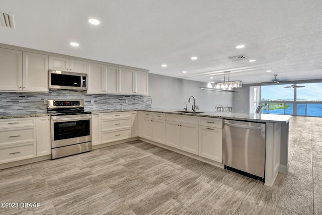 kitchen with stainless steel appliances, sink, a water view, and light wood-type flooring