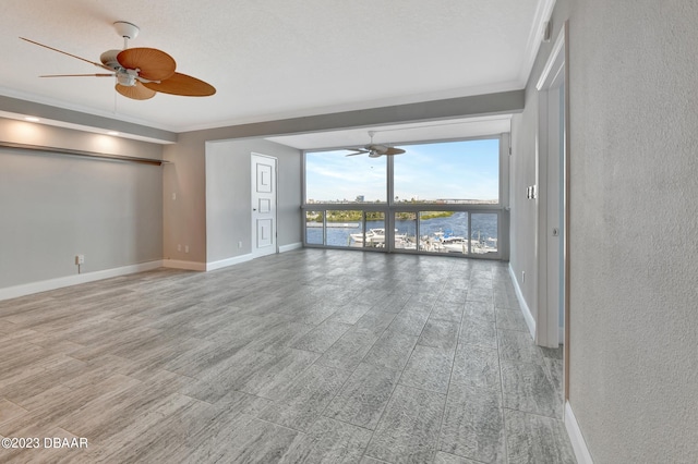 unfurnished room featuring ceiling fan, a water view, and ornamental molding