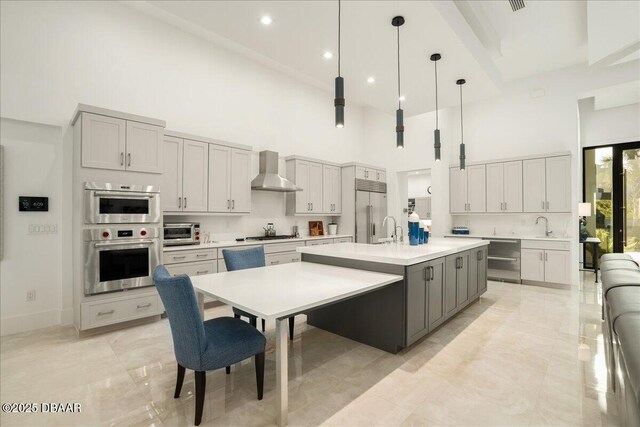 634 Woodbridge Dr, Ormond Beach, FL 32174 - kitchen featuring a high ceiling, wall chimney range hood, gray cabinetry, stainless steel appliances, and light countertops