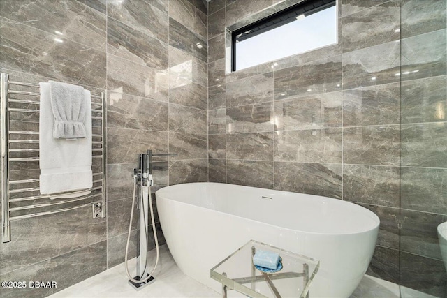 634 Woodbridge Dr, Ormond Beach, FL 32174 - bathroom with radiator, tile walls, a towel warming rack, and a soaking tub