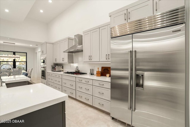 634 Woodbridge Dr, Ormond Beach, FL 32174 - kitchen featuring stainless steel appliances, wall chimney range hood, a sink, a high ceiling, and recessed lighting