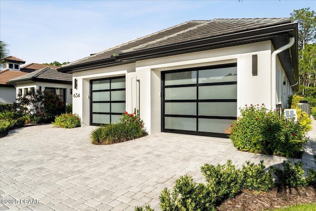 634 Woodbridge Dr, Ormond Beach, FL 32174 - garage featuring central AC unit and decorative driveway