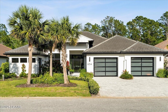 634 Woodbridge Dr, Ormond Beach, FL 32174 - view of front of home with a garage, stucco siding, decorative driveway, a front yard, and a tile roof