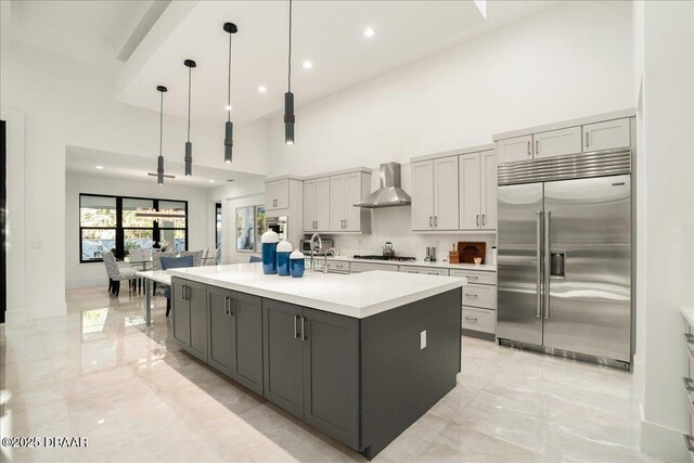 634 Woodbridge Dr, Ormond Beach, FL 32174 - kitchen with stainless steel built in refrigerator, gray cabinetry, light marble finish flooring, wall chimney range hood, and a towering ceiling