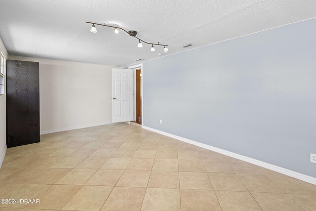 tiled empty room with a textured ceiling