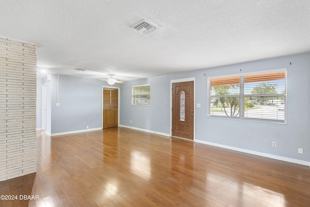 empty room with ceiling fan, a textured ceiling, and light wood-type flooring