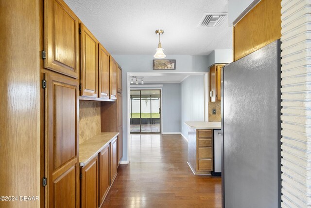 kitchen with dark wood-type flooring, a textured ceiling, and decorative light fixtures