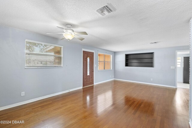 unfurnished living room with a textured ceiling, hardwood / wood-style flooring, and ceiling fan