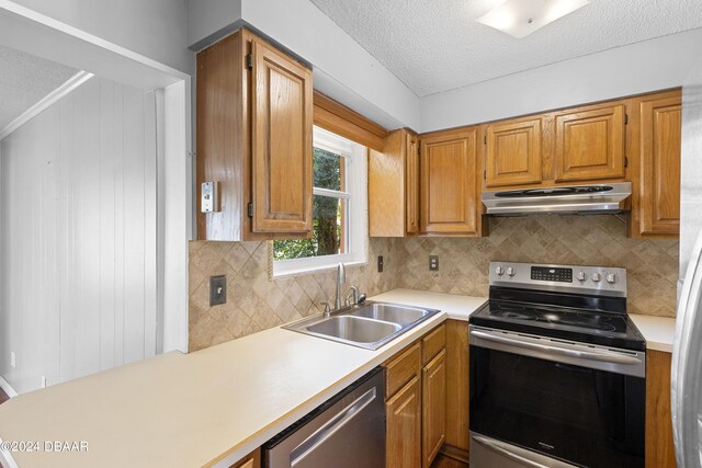 kitchen with crown molding, backsplash, appliances with stainless steel finishes, a textured ceiling, and sink