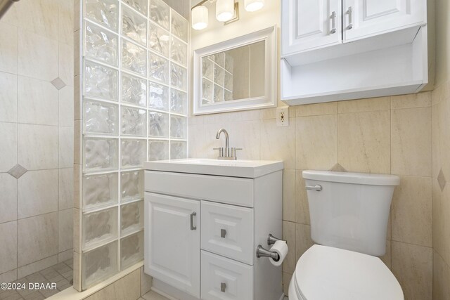 bathroom featuring walk in shower, vanity, and tile walls