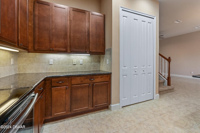 kitchen featuring dark stone counters, decorative backsplash, and light tile patterned floors