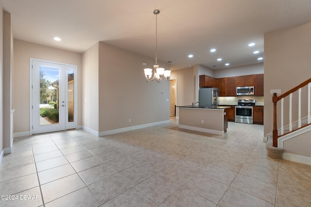 kitchen featuring stainless steel appliances, a chandelier, light tile patterned floors, an island with sink, and pendant lighting