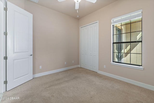 unfurnished bedroom featuring ceiling fan, light carpet, and a closet