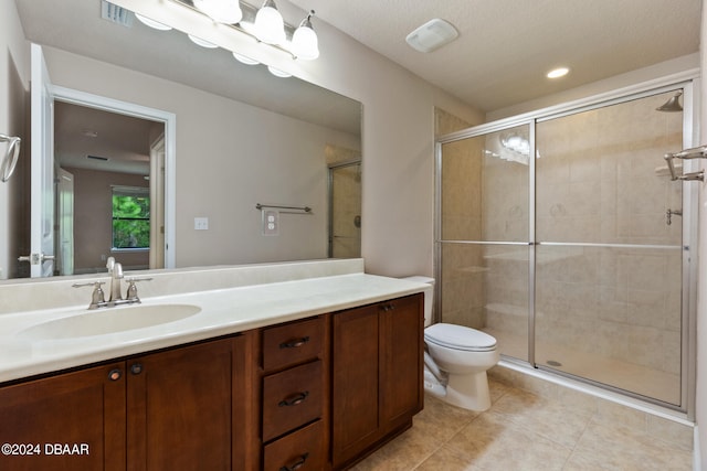 bathroom with toilet, vanity, tile patterned floors, and a shower with shower door