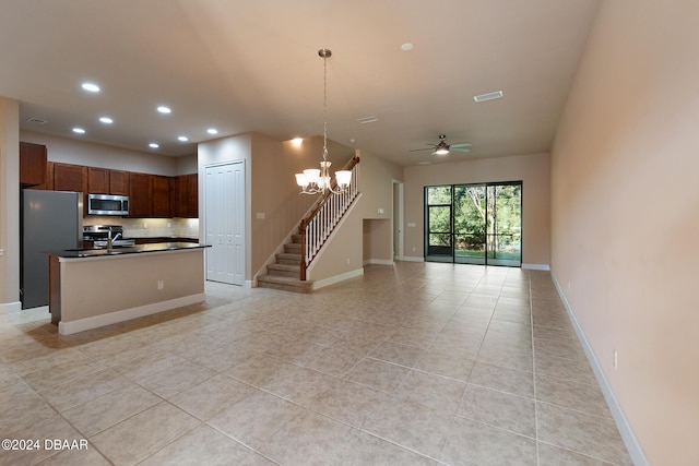 kitchen featuring tasteful backsplash, stainless steel appliances, pendant lighting, an island with sink, and ceiling fan with notable chandelier