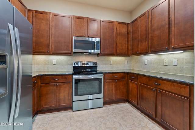 kitchen featuring dark stone countertops, decorative backsplash, and stainless steel appliances