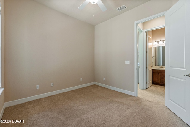 unfurnished bedroom featuring ceiling fan, ensuite bath, and light carpet