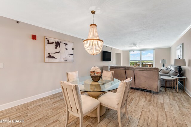 3797 S Atlantic Ave Unit 404, Daytona Beach, FL 32118 - dining area featuring light wood finished floors, a chandelier, baseboards, crown molding, and a ceiling fan