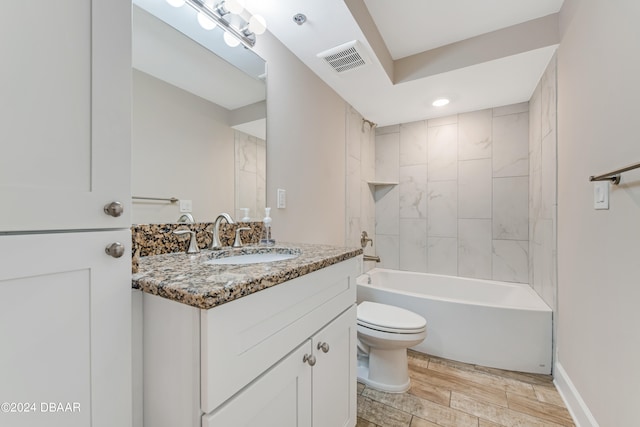 full bathroom with tiled shower / bath, hardwood / wood-style floors, vanity, and toilet