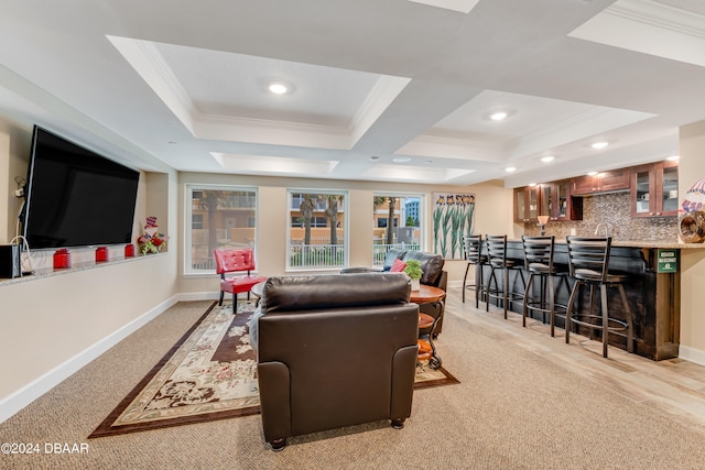 living room featuring coffered ceiling, crown molding, indoor bar, a tray ceiling, and light colored carpet