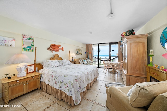 bedroom with access to outside, floor to ceiling windows, a textured ceiling, and light tile patterned floors