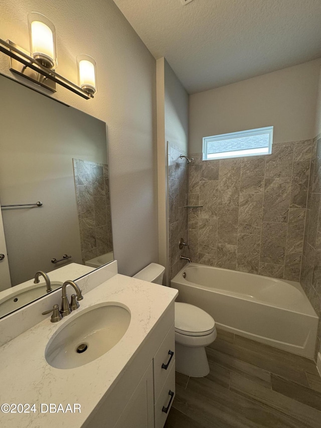 full bathroom featuring tiled shower / bath, a textured ceiling, toilet, vanity, and hardwood / wood-style flooring