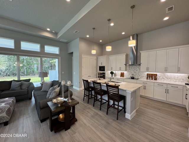 living room with light wood-type flooring, a towering ceiling, and sink