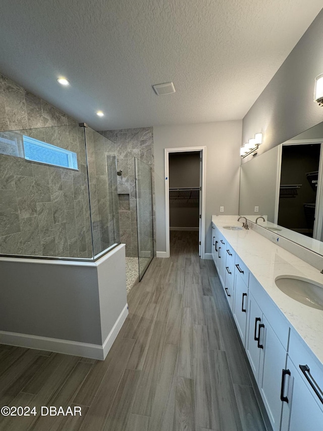 bathroom featuring vanity, wood-type flooring, a textured ceiling, and tiled shower