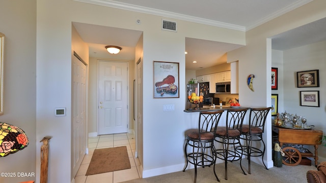 kitchen featuring appliances with stainless steel finishes, kitchen peninsula, light tile patterned floors, a kitchen bar, and white cabinetry